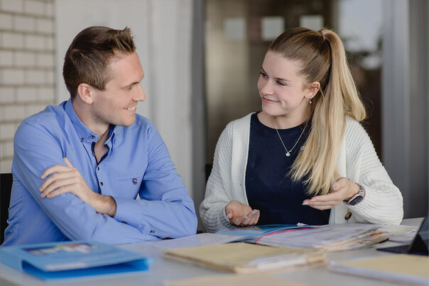 Junger Mann und junge Frau im Gespräch sitzend an einem Tisch